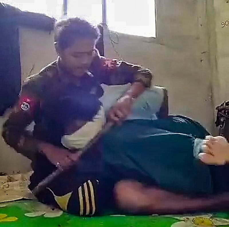 မျက်နှာတွင်အဝတ်စည်းကာ လက်နောက်ပြန်ကြိုးတုပ်ပြီး ဖမ်းဆီးခံထားရသည့် အရပ်သားကို စစ်ကောင်စီတပ်သားက ညှဉ်းပန်းနှိပ်စက်နေစဉ်။ (RFA screenshot from video)