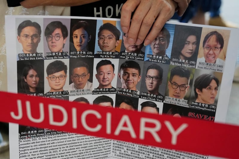 2021年7月8日,一名支持者在香港法院外举着标语牌声援47名民主被告的照片。(美联社)